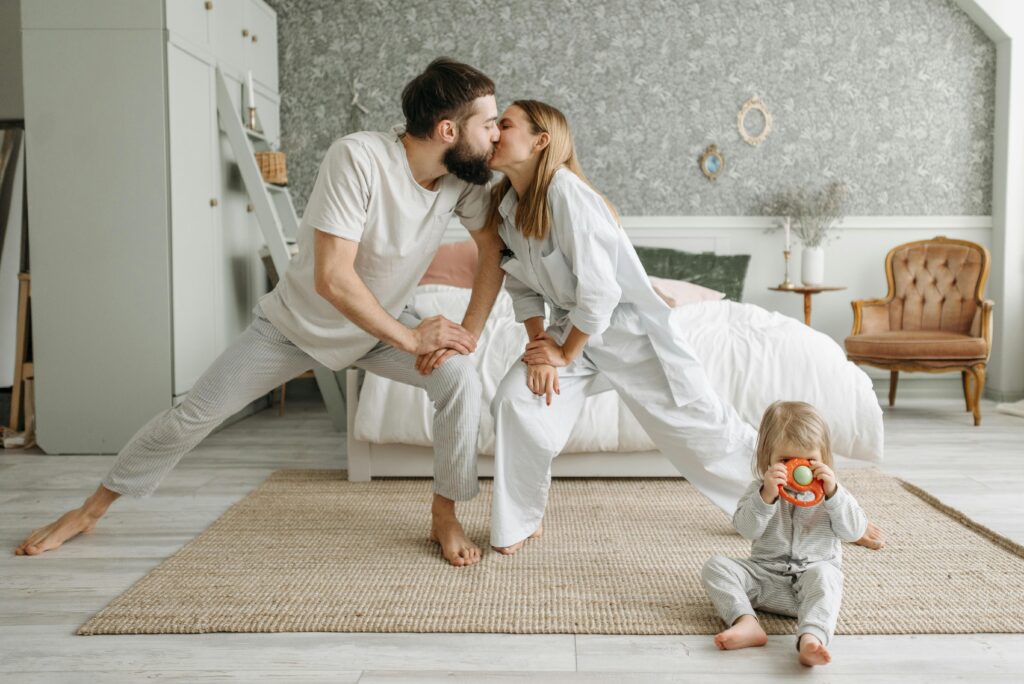 Playful morning with parents stretching and a toddler playing in the bedroom.